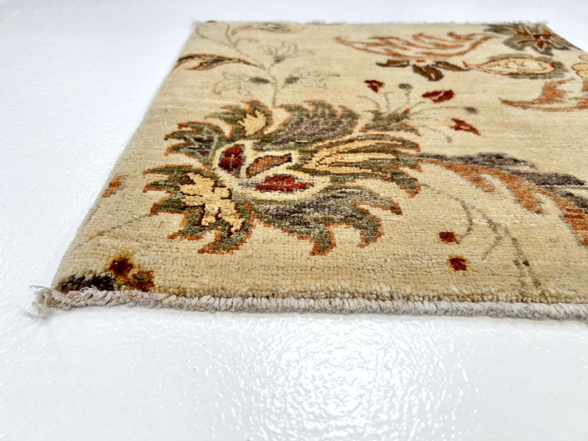Corner of 18" square ivory rug features vegetable-dyed wool with luxurious silk accents