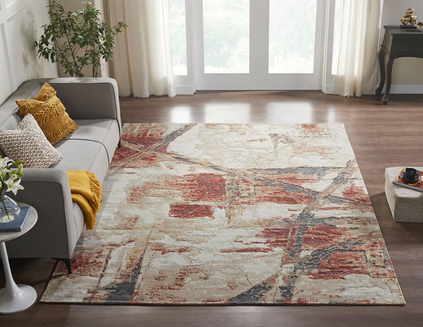 Grey couch in living room setting with Rust/Sand Abstract Area Rug -Vaughn Collection